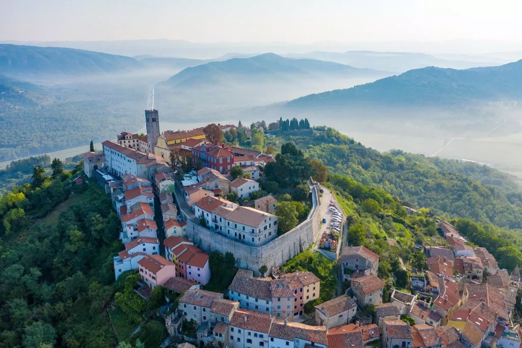 Ancient city Motovun on top of the mountain.The city is surrounded by a fortress wall.The background image are mountains and fog at the foot of the mountains. Istria, Croatia.The view from the drone.