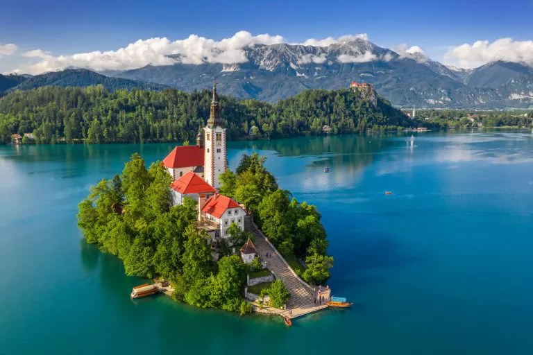 Bled, Slovénie - Vue aérienne du magnifique lac de Bled (Blejsko Jezero) avec l'église de pèlerinage de l'Assomption de Maria sur une petite île, le château de Bled et les Alpes Juliennes en arrière-plan, en été.