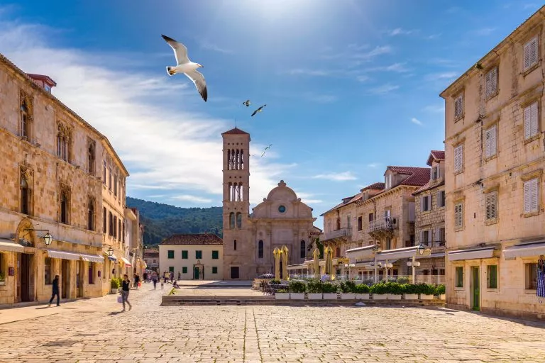 Place principale de la vieille ville médiévale de Hvar, survolée par des mouettes. Hvar est l'une des destinations touristiques les plus populaires de Croatie en été. Place centrale Pjaca de la ville de Hvar, Dalmatie, Croatie.